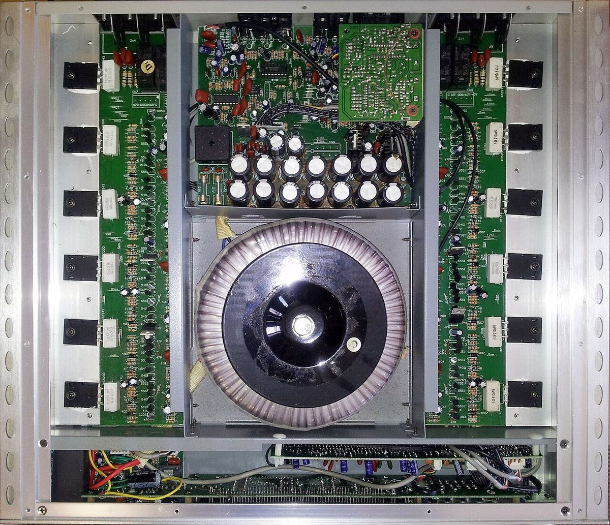Top view inside a YBA multi-channel power amplifier with a large toroidal transformer and rows of output devices
