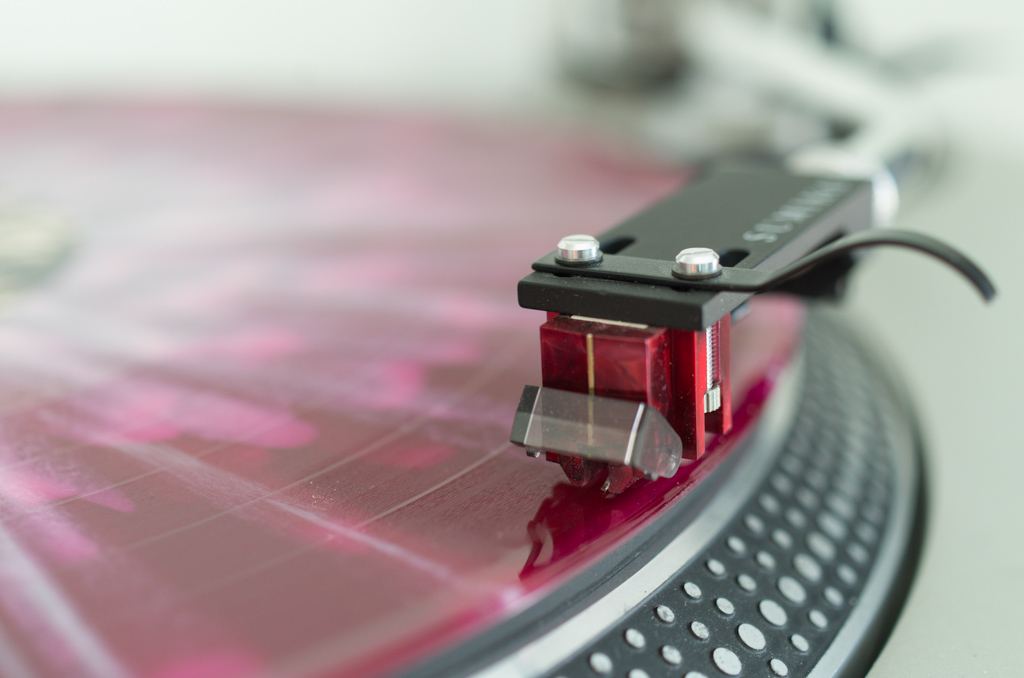 Red Denon DL-110 phono cartridge playing a red vinyl record
