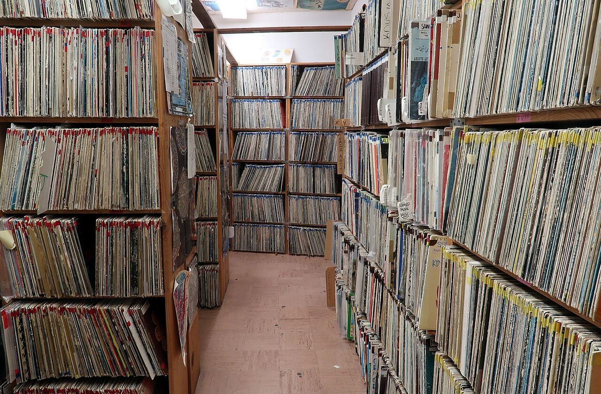 Floor-to-ceiling shelves of vinyl records stored upright at a radio station library