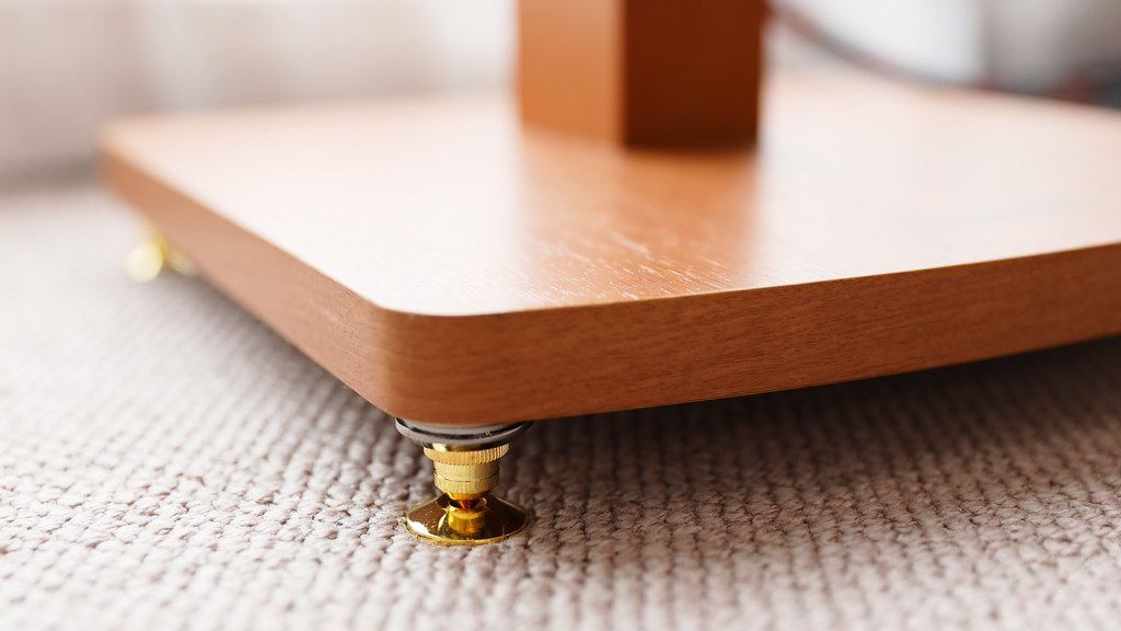 Brass spike foot under the wooden base of a speaker stand